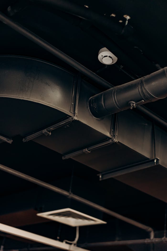 impact-img Detailed view of industrial air ducts on a ceiling, showcasing modern urban design.